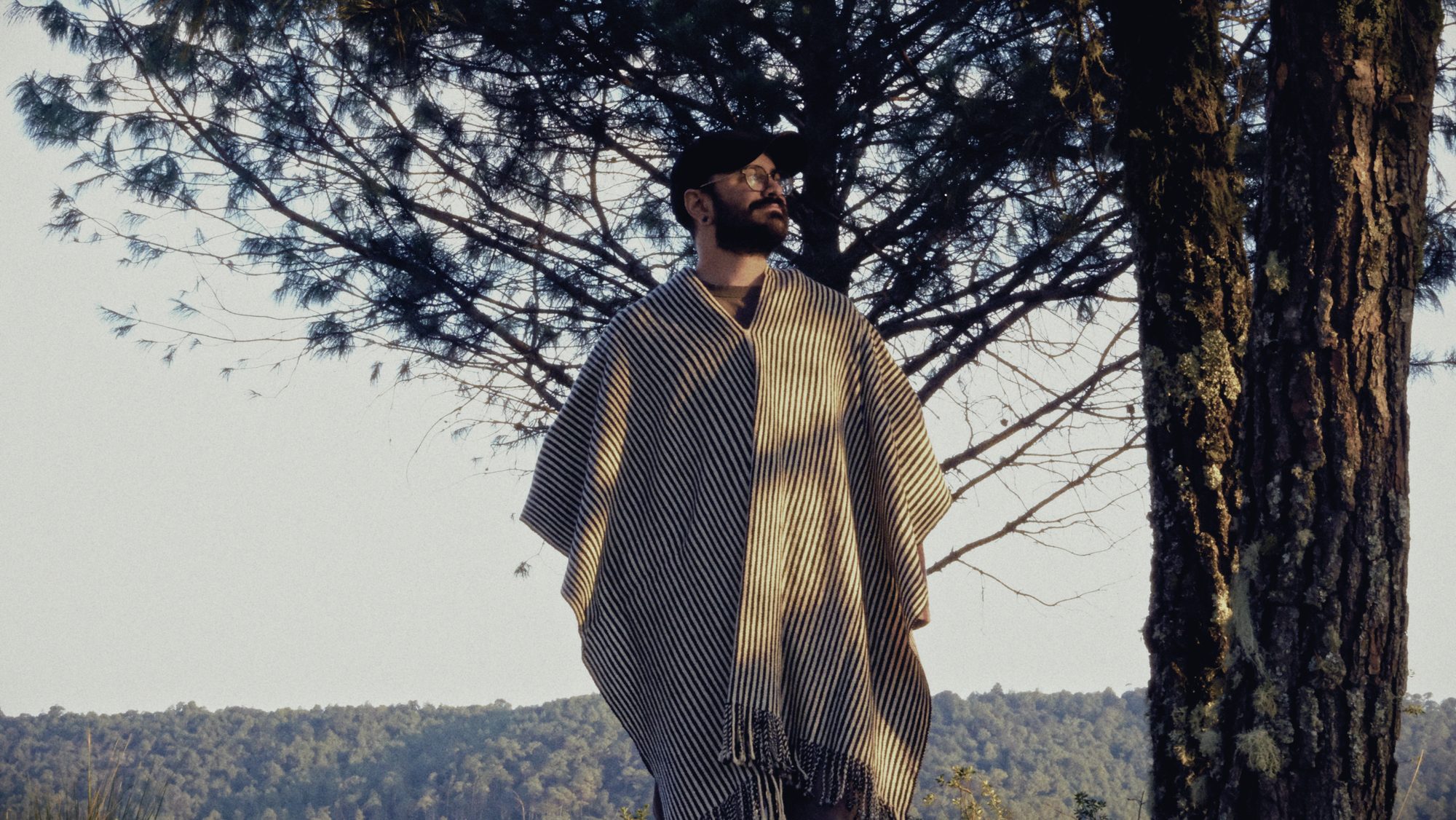 losiento in a striped poncho under a pine at golden hour